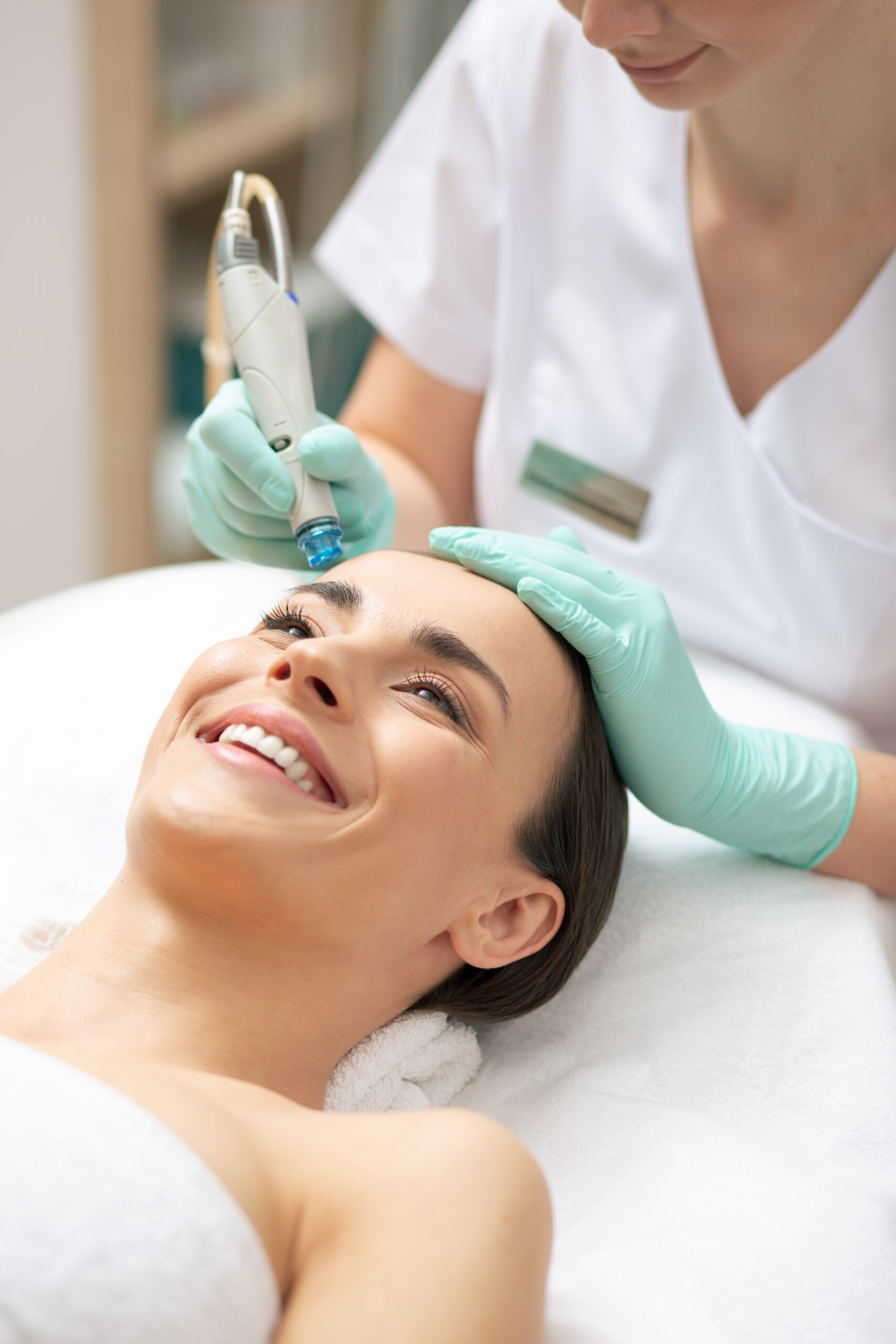 cheerful young lady looking happy smiling while professional beautician using special tool nourishing skin her face scaled